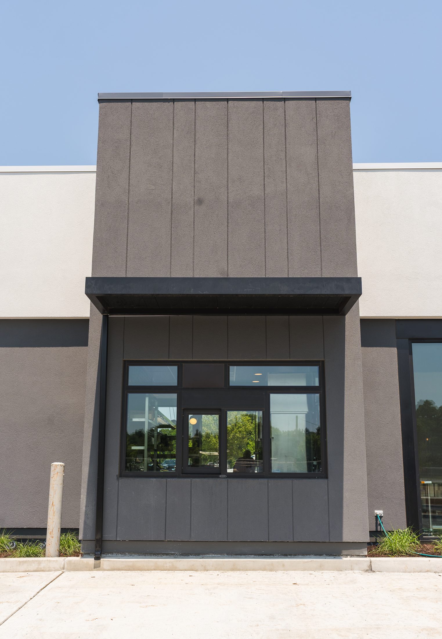 Dark flat-panel canopy detail over a window on a modern commercial facade by Manchester Awning