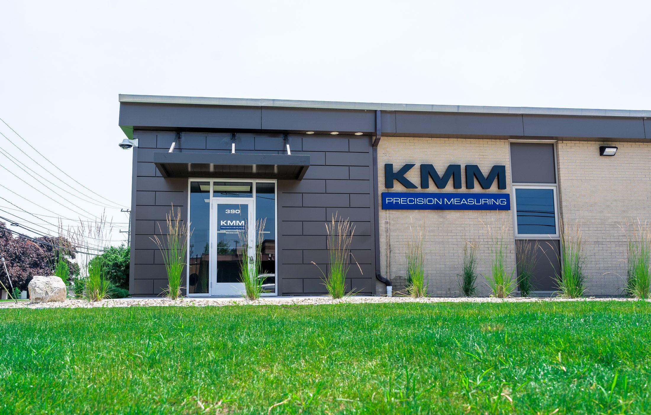 Black metal entrance canopy over the door at KMM Precision Measuring with landscaped grounds by Manchester Awning
