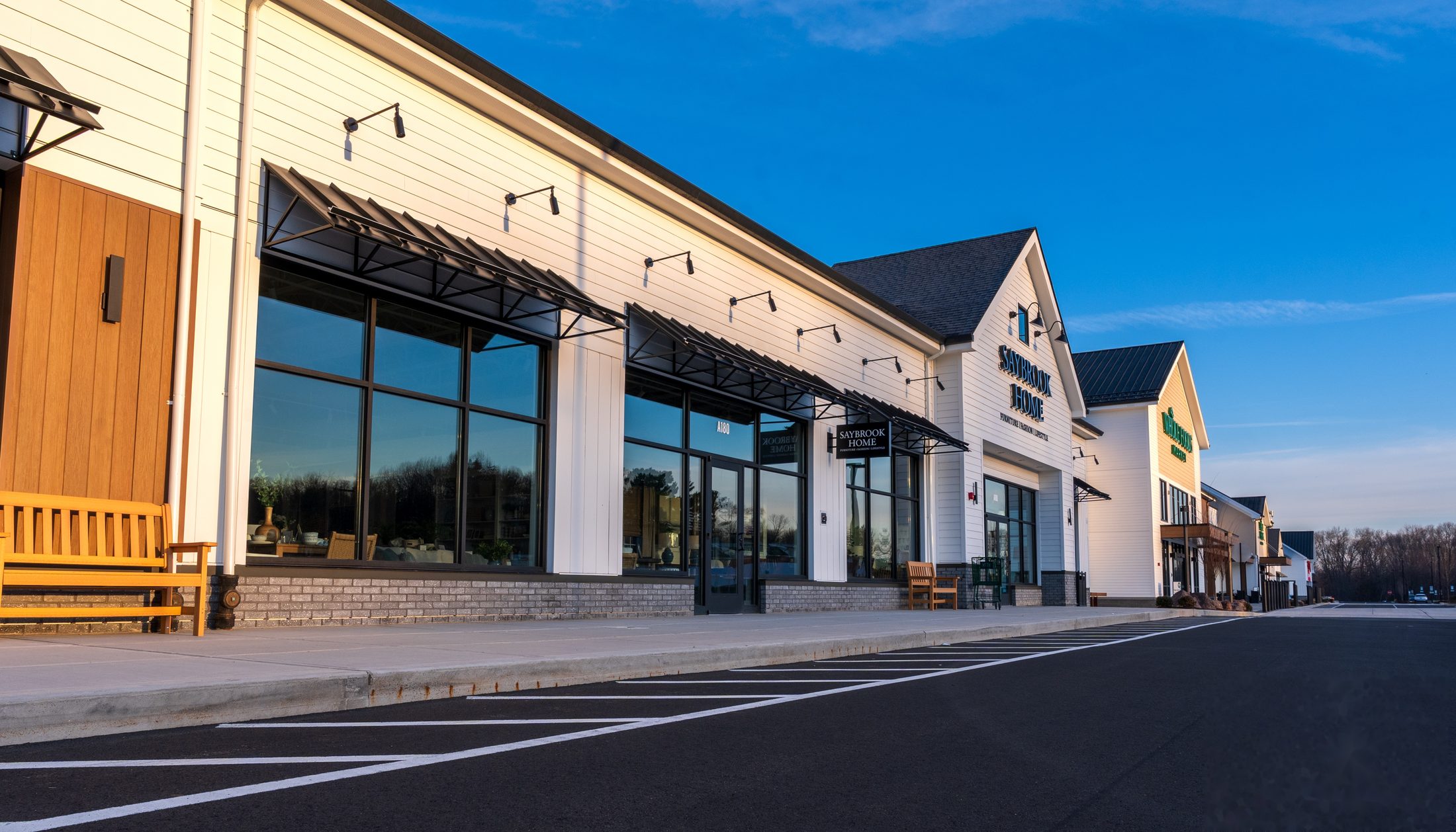 Row of black standing-seam metal window awnings on an upscale Connecticut retail plaza at golden hour by Manchester Awning