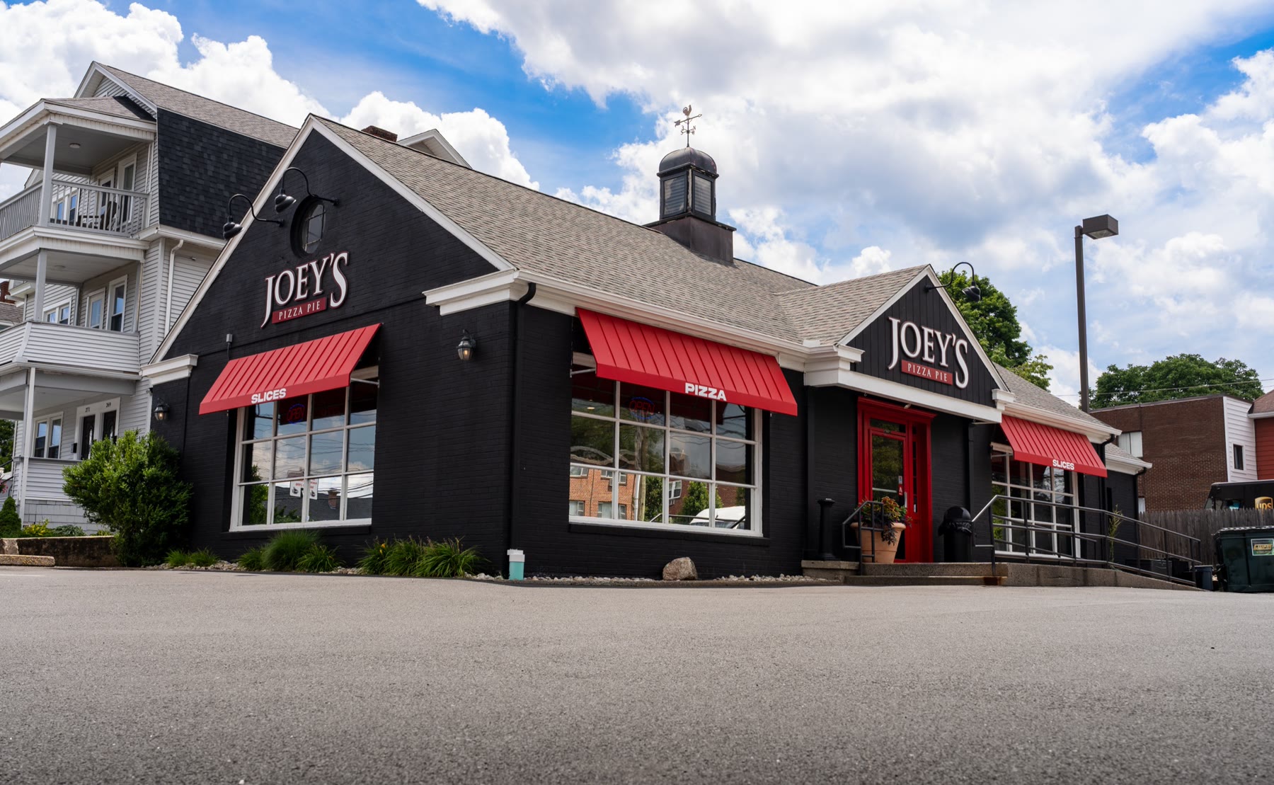 Wide establishing shot of Joey's Pizza Pie in Connecticut with red standing-seam awnings and gabled roof, installed by Manchester Awning