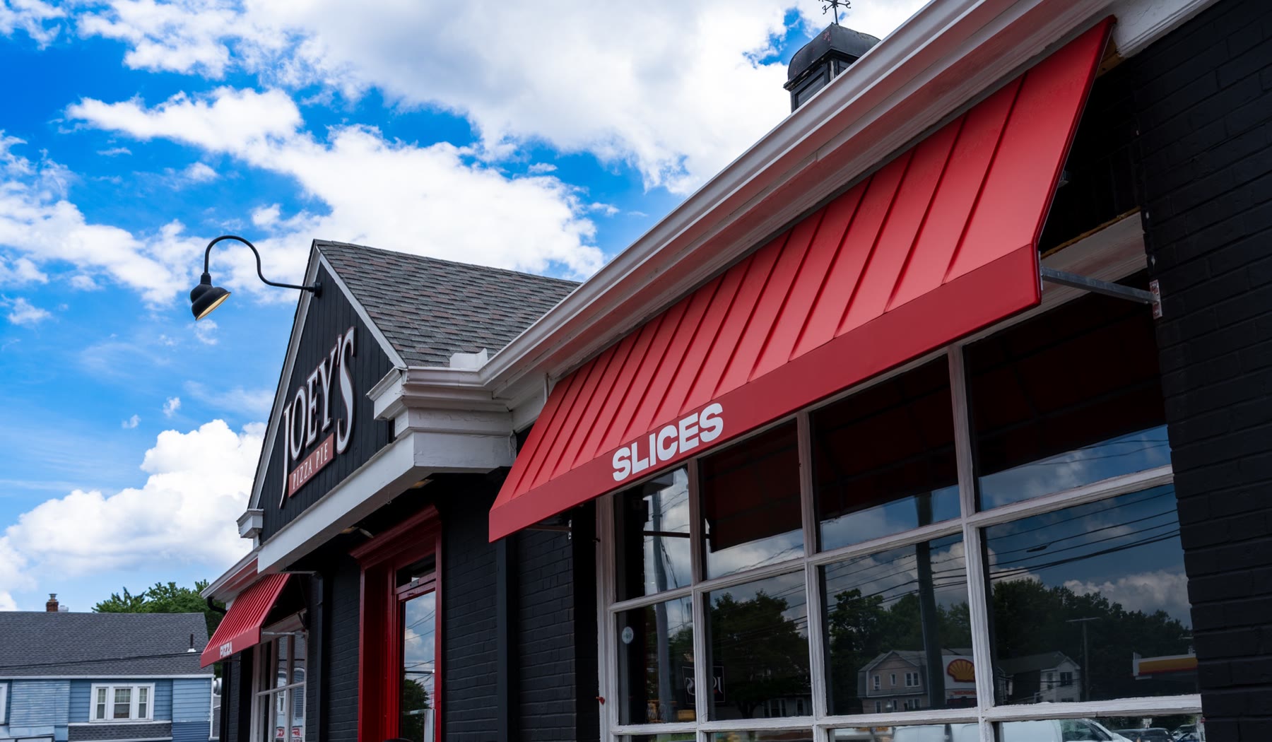 Close-up of the crisp vertical standing-seam ribs on a red fabric awning against a blue sky, by Manchester Awning