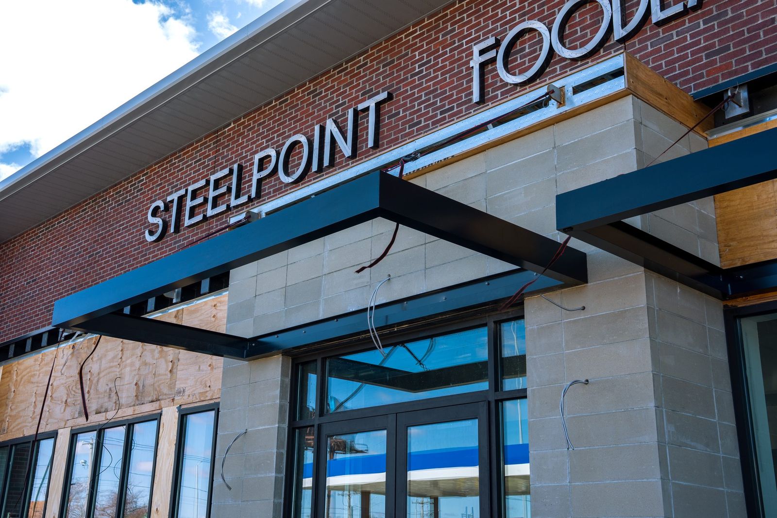 Close detail of the black cantilevered metal entrance canopy structure at Steelpointe Foodland by Manchester Awning
