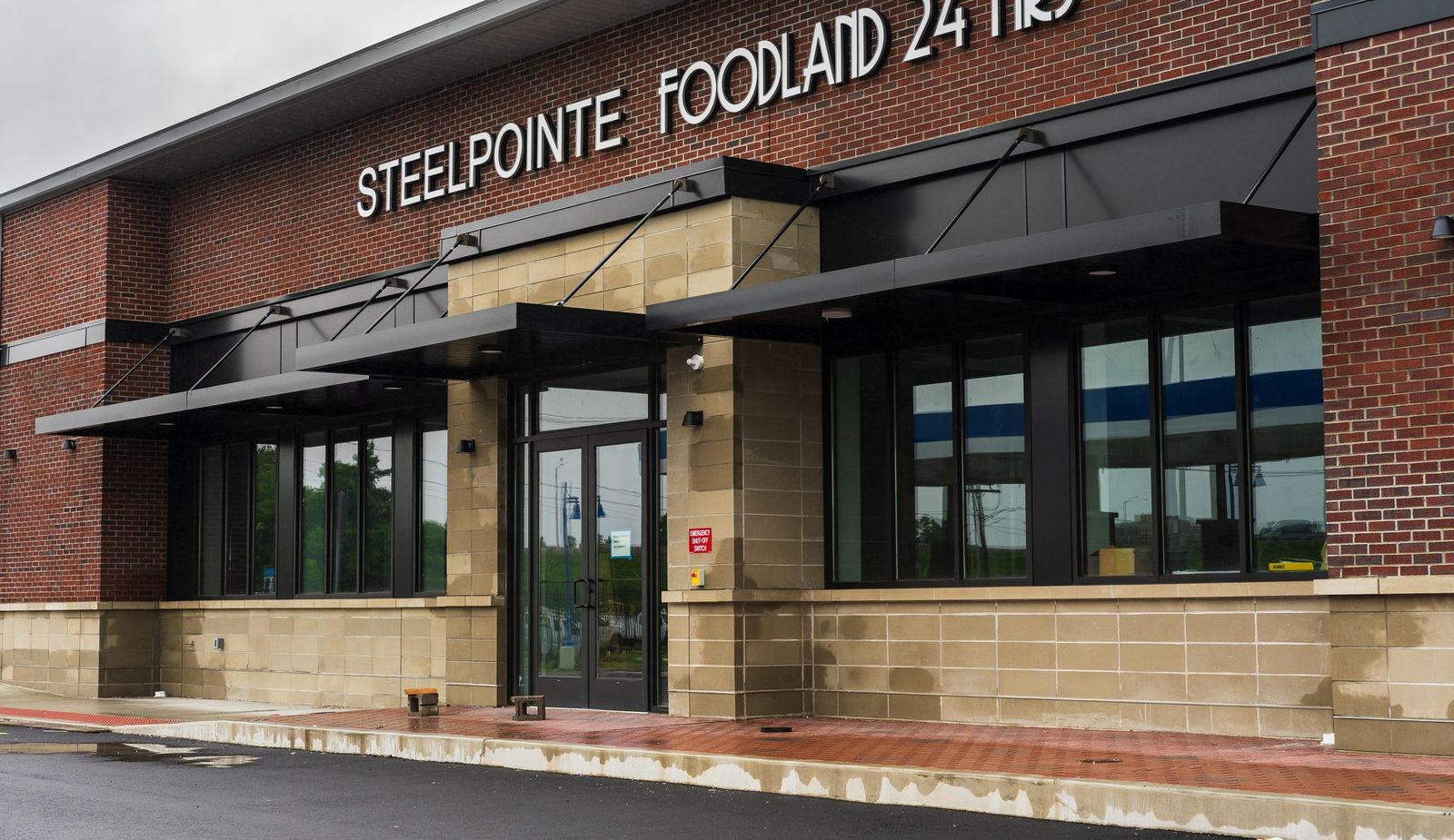 Black cantilevered metal entrance canopy over the doors at Steelpointe Foodland by Manchester Awning