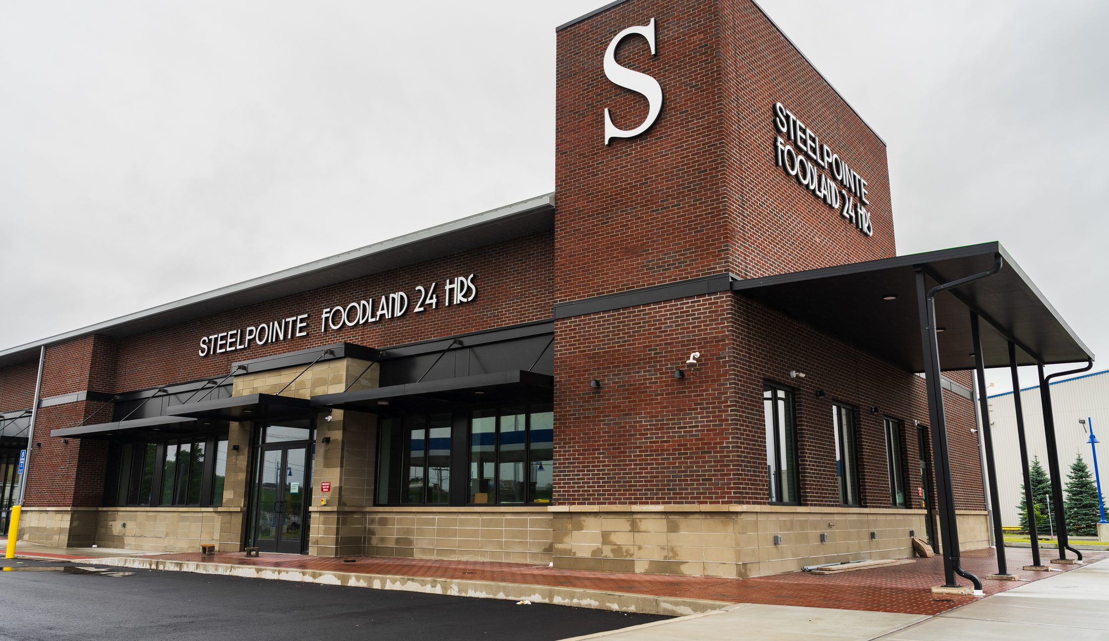 Finished Steelpointe Foodland supermarket with black architectural metal canopies and signage tower by Manchester Awning