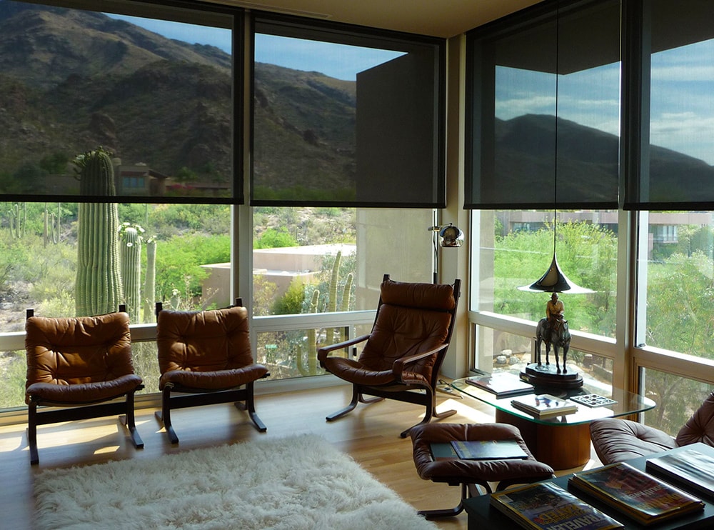 View from inside a screened room with Freedom screens lowered over full-height glazing, looking out to the landscape beyond