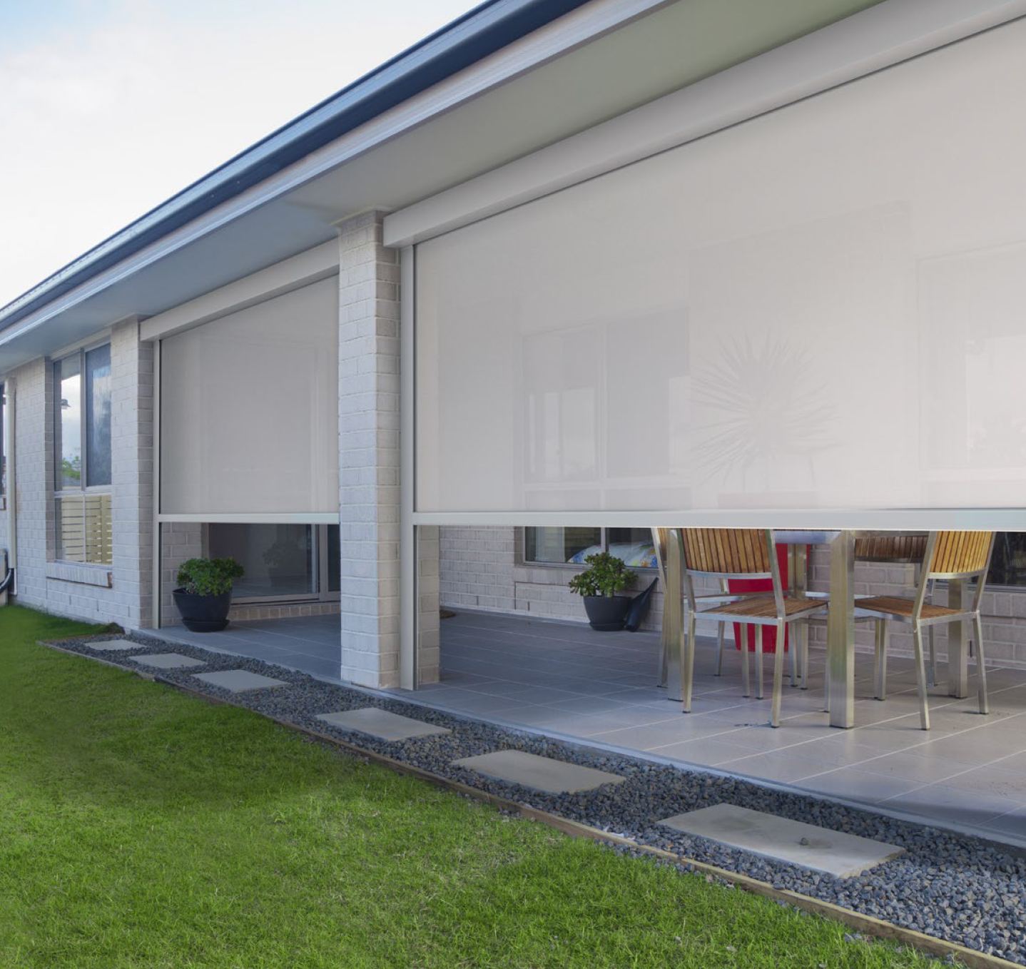 Freedom retractable screens lowered on a covered porch, shading the furnished deck behind them