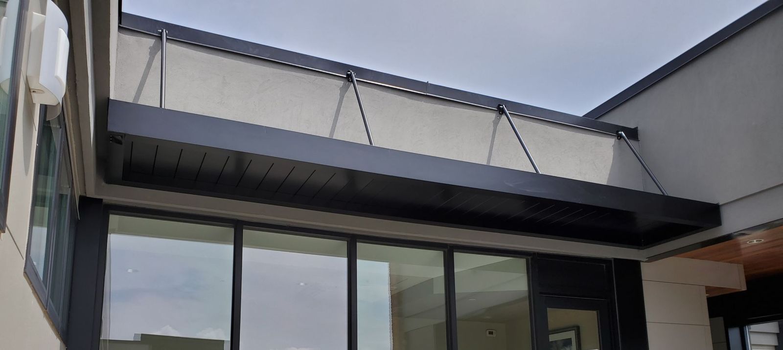 Frontier architectural canopy in white and dark bronze spanning full-height windows on a contemporary building