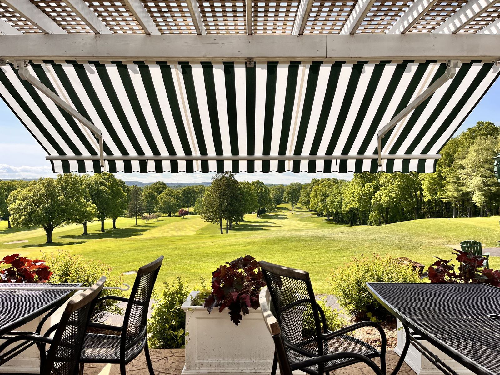 Legend awning extended over a patio overlooking a golf course, showing the full projection with no front support posts