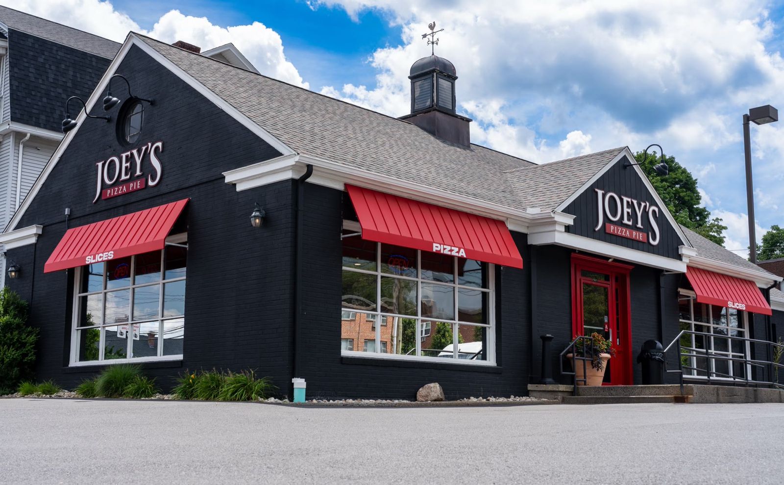 Deep red standing-seam Metal Look awnings across a storefront
