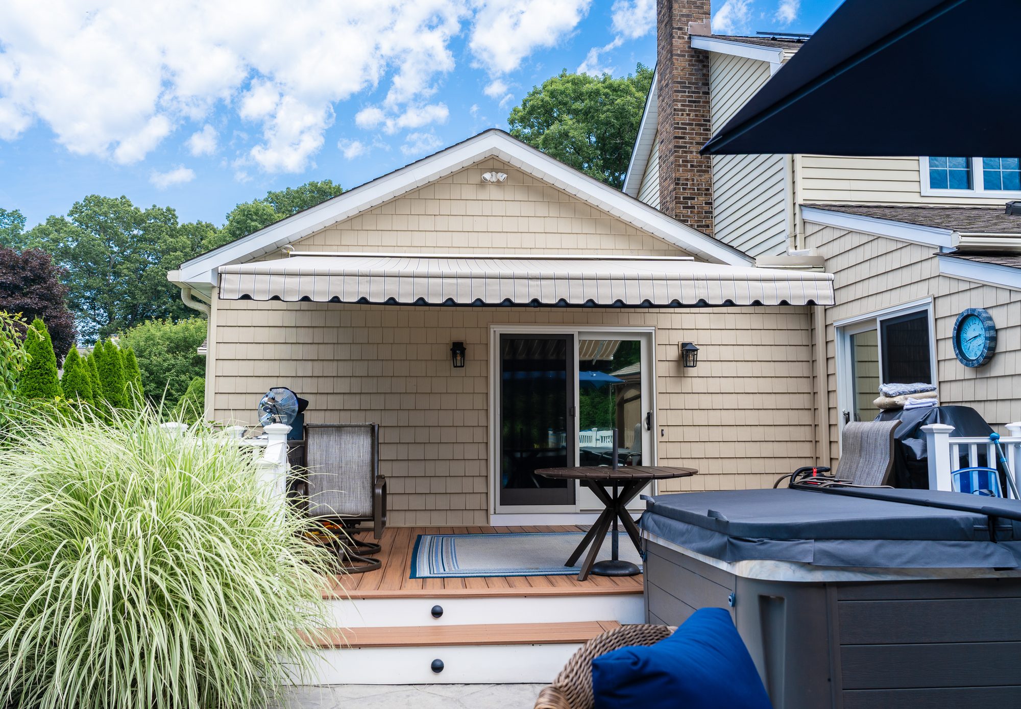 Retractable awning shading a Connecticut backyard deck with a hot tub by Manchester Awning