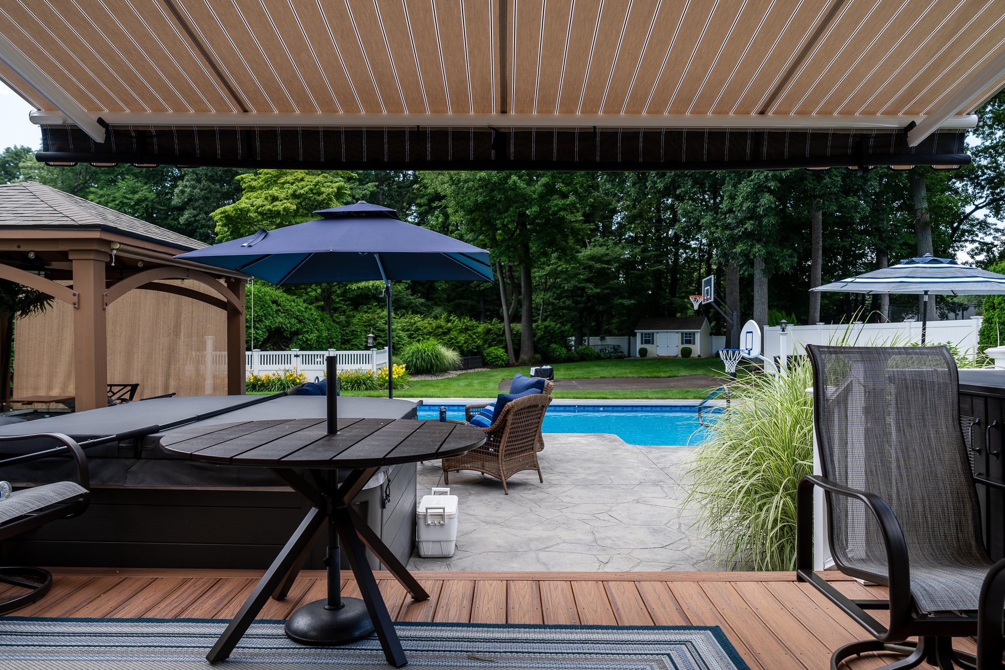 View from under a retractable awning over a Connecticut backyard pool by Manchester Awning