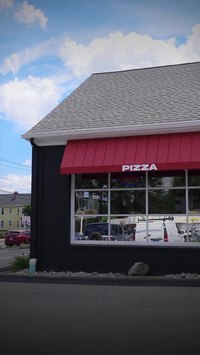 A standing-seam metal-look awning above a storefront entrance, its raised ribs catching the afternoon light